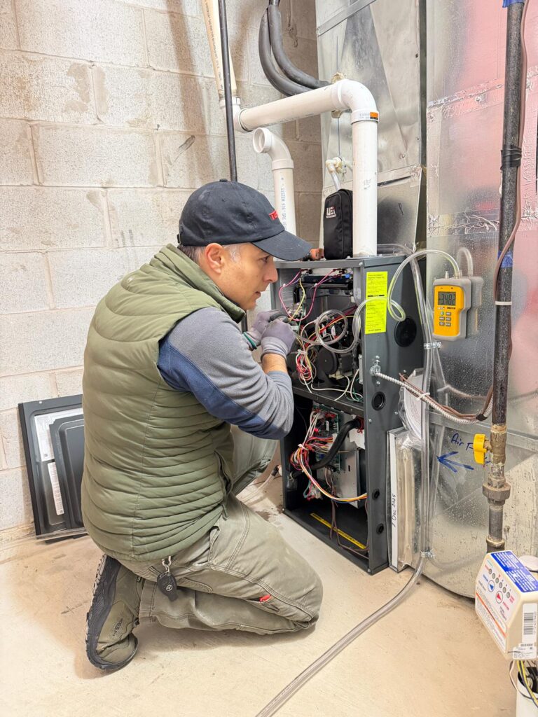 Furnace repair technician inspecting and fixing a home heating system during professional HVAC maintenance