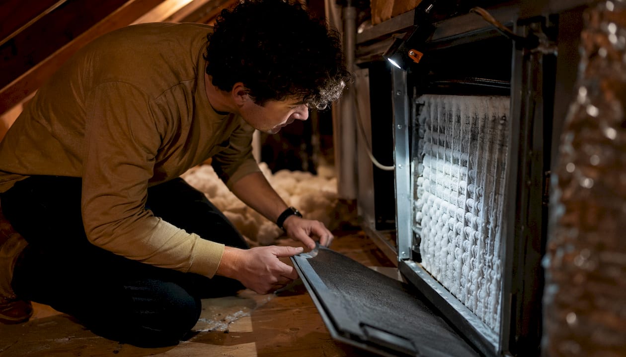 Homeowner examining frozen evaporator coil inside closet
